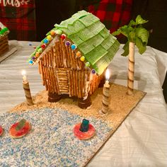 a gingerbread house made to look like it is on top of a table with candles