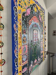 a colorful painting on the wall next to a stair case with beads hanging from it