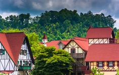 a row of houses with red roofs and trees in the foreground, on a cloudy day