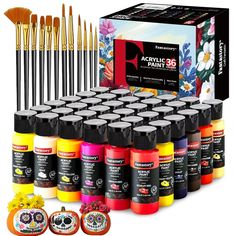 an assortment of acrylic paint and brushes in front of a box with flowers