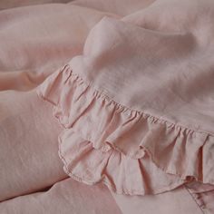 pink sheets with ruffles on them laying on top of each other in a bed