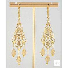 Add some radiance and enchantment to your style with these stunning yellow champagne filigree earrings! The sparkling yellow champagne-colored glass teardrop beads are perfectly accented by shimmery white glass beads, all set in intricate gold-plated filigree and lever backs. These dangling earrings, measuring 2.75 inches, will definitely catch attention. Elevate any ensemble with these gorgeous yellow glass and gold filigree earrings.