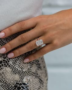 a woman's hand with a diamond ring on her left wrist, wearing a snake skin skirt