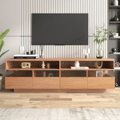 a living room with a large television on top of a wooden entertainment center next to a potted plant