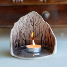 a lit candle sitting on top of a table next to a wooden box and drawer