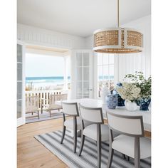 a dining room table with chairs and vases on top of it next to the ocean