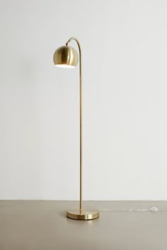 a floor lamp on a table with a white wall in the background and a gold base