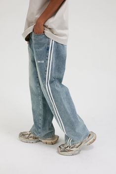 The Washed Striped Wide-Leg Pants seamlessly blend vintage style with contemporary craftsmanship. Featuring an all-over washed and distressed look, these pants are adorned with embroidered logos on each hip. The striking contrast stripes run from the back waist down the front of the legs, enhancing the body’s natural silhouette. Functional front pockets are decorated with rivets, while two back pockets provide additional utility. Crafted from premium fabric, these slightly oversized pants offer Trend Jeans, 51 Kg, Light Wash Denim Jeans, Oversized Pants, Mens Cardigan Sweater, Cami Shirt, Varsity Jacket Men, Vest Blazer, Jean Trends