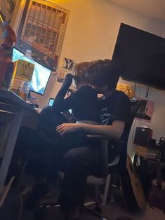 two boys sitting at a computer desk with their arms around each other's shoulders