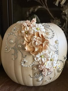 a white pumpkin decorated with flowers and pearls