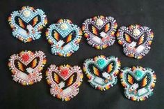 six heart shaped beaded brooches on a black background