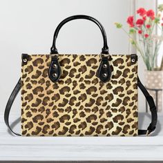 This handbag features PU leather as its main material and is adorned with an all-over leopard print in a customized style. It also boasts a smooth zipper and is available in three sizes: Medium, Large, and X-Large. The straps, handles, and threads come in two different colors. For comfortable carrying and balance, it has two sturdy top handles. There's also an inside pocket with a removable, adjustable strap for different styling options. This handbag makes for a perfect gift for girls, moms, and office ladies. It's suitable for both commuting and traveling, and can easily hold your cell phone, wallet, and other daily essentials. If you choose the XL size, you can even fit your laptop and documents inside! CARE INSTRUCTIONS: Regular wiping is recommended with cold water and a wet cloth. An Leopard Print Rectangular Shopping Bag, Leopard Print Large Capacity Satchel Bag, Trendy Rectangular Leopard Print Bags, Rectangular Leopard Print Bags For Daily Use, Leopard Print Large Capacity Satchel Shoulder Bag, Large Capacity Leopard Print Satchel Shoulder Bag, Trendy Leopard Print Tote Bag, Leopard Print Travel Bag With Animal Design, Brown Shoulder Bag With Animal Design For Daily Use