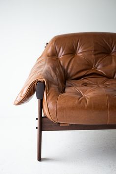 a brown leather chair sitting on top of a white floor next to a wooden frame