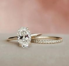 two gold wedding rings with diamonds on the sides and an oval shaped diamond in the middle