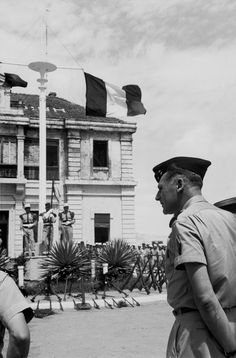 black and white photograph of two men in uniform talking to each other outside an old building