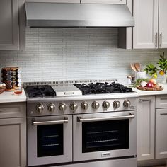 a stove top oven sitting inside of a kitchen next to white cupboards and drawers