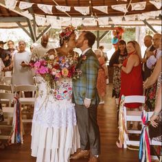 a bride and groom kiss as they walk down the aisle after their wedding ceremony at an outdoor venue