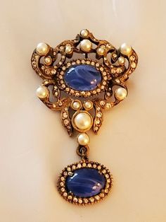 "Quality abounds in this spectacular brooch and pendant, signed DeNicola. It's in the most excellent condition and embodies the outstanding design elements of the finest costume jewelry. DeNicola is revered for for some of its finest lines of jewelry, and this brooch in no exception to that quality. The flawed sapphires are sensational and combine with pearls and tiny rhinestones to enchant its design. Every stone is perfect. A pendant detachment is built into the construction of the back and al Victorian Pendant Brooches With Cabochon, Oval Brooch For Vintage Events, Victorian Pendant Brooch With Jewels, Vintage Jeweled Brooch For Anniversary, Vintage Brooch Jewelry For Evening, Vintage Brooch For Evening, Vintage Jeweled Brooches For Anniversary, Vintage Jewel Brooches For Anniversary, Vintage Jewels Brooches For Anniversary