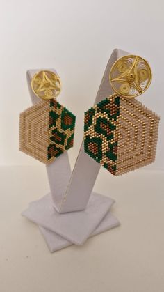 These elegant earrings feature a unique hexagonal design, handcrafted with delicate Miyuki beads in beige, gold, and green tones that create a geometric pattern. The contrast between the colors brings a bold and sophisticated design to life. The top of the earrings has a round detail made of bronze filigree plated in 24-karat gold, adding a luxurious and artisanal touch. Length: 5 cm Width : 4 cm Each piece is unique and reflects the delicacy and precision of the artisanal technique. Please feel free to reach out to us with special requests. Custom orders could take up to 2 months Thank you Handmade Geometric Gold Earrings, Gold Geometric Beaded Earrings As A Gift, Gold Geometric Beaded Earrings For Gift, Geometric Beaded Gold Earrings, Gold Beaded Geometric Earrings, Geometric Gold Beaded Earrings, Gold Geometric Beaded Earrings, Geometric Beaded Gold Jewelry, Traditional Faceted Beads Earrings For Gift