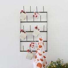 tea cups are hanging on the wall near a potted plant and mugs with hearts