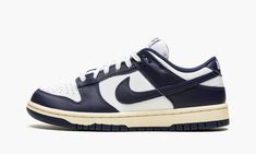 The Nike Dunk Low “Vintage Navy” is a classic two-tone, white-and-navy colorway for the retro basketball shoe with a decidedly throwback vibe.  The “Vintage Navy” edition of the Dunk Low calls back to original styles found in the “Be True to Your School” pack of college basketball-inspired colorways from 1985.  The shoe’s upper features a white leather base with contrasting Vintage Navy-colored leather overlays and Swoosh branding.  White “Nike” branding is embroidered on the heel, and navy “Nik Nike Dunk Low Vintage Navy, Nike Heels, School Pack, Retro Basketball Shoes, Nike Branding, Retro Basketball, Nike Brand, Nike Vintage, Navy Shoes