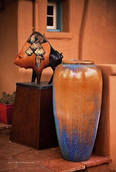 two vases sitting next to each other in front of a tan building with blue windows