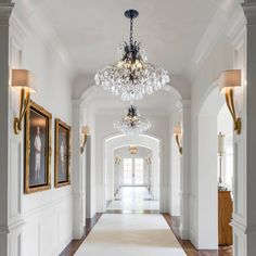 an elegant hallway with chandelier and pictures on the wall in front of it