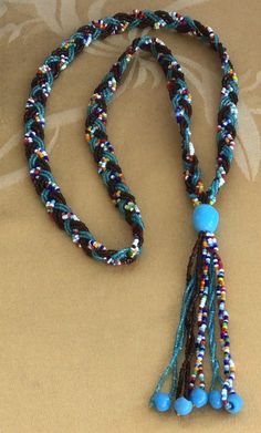 "Featuring this unique blue, brown and multi-colored glass seed bead woven tassel necklace. The necklace measures 28\", not including the tassel. It is in very good vintage condition and does not have a clasp." Turquoise Beaded Necklace With Tassels And Round Beads, Turquoise Beaded Necklace With Tassels, Multicolor Tassel Necklace With Round Beads For Beach, Adjustable Multicolor Beaded Necklaces With Tassels, Multicolor Round Beaded Tassel Necklace For Beach, Multicolor Round Beads Tassel Necklace For Beach, Adjustable Multicolor Tassel Necklace With 108 Beads, Bohemian Blue Beaded Necklaces With Tassels, Adjustable Multicolor Tassel Necklace With Round Beads