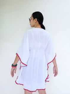 "🚚..ALL ORDERS ARE SHIPPED VIA DHL EXPRESS MAIL Opt for the perfect beach cover up with this white kaftan cut with kaftan sleeves, v-neck with drawstring tie closure and pom pom trim along edges. Layer it over your brightly color bikinis for a beach ready look. It's an irresistibly stylish choice for sun-soaked getaways. * Pull-on style * V-neck with drawstring tie closure * Kaftan sleeve. * Red, white and blue pom pom trim along edges * Ruched waistline detail at center front and center back * Traditional Spring Kaftan With Back Tassel Tie-up, White V-neck Bohemian Kimono, Traditional Kaftan With Back Tassel Tie-up For Spring, White V-neck Kimono For Festival, Traditional V-neck Kaftan With Tassels, Red Kimono For Beach Cover-up, Summer Beachwear Kaftan With Back Tassel Tie-up, Traditional Kaftan With Back Tassel Tie-up For Festivals, Traditional Festival Kaftan With Back Tassel Tie-up