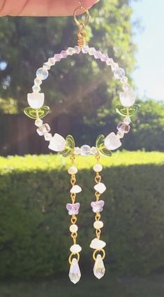 a person is holding up a necklace made from glass beads and gold chains with charms