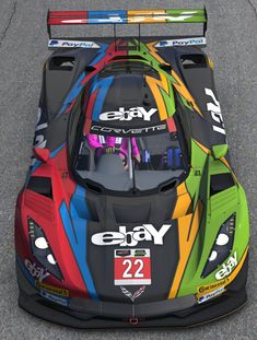 a colorful race car is driving down the road with its hood up and numbers painted on it