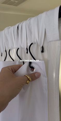 a person is holding onto a white shirt hanging on a rack with black ties and gold rings