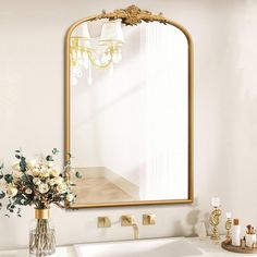 a bathroom sink with a mirror above it and flowers in a vase on the counter