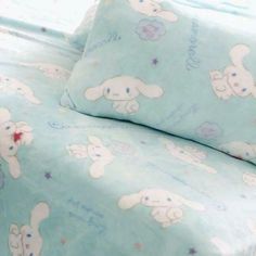 a bed covered in blue sheets with white rabbits on them and stars around the edges