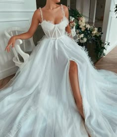 a woman in a white wedding dress sitting on a chair and posing for the camera