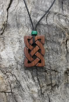 a wooden necklace with an intricate design on it's cord hanging from a tree