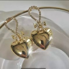 This Is A Very Beautiful Pair Of Gold Plated Metal Heart Dangle Earrings . They Have A Bow Made Of Baguette Cz Stones And The Top Of Earrings Have Pave Cz Stones . The Length Is 3.8 Inches And The Hearts Are A Puffed Heart Design . Elegant Heart Pendant Earrings For Party, Elegant Heart Earrings For Party, Metal Earrings With Heart Charm For Party, Elegant Rhinestone Heart Earrings As Gift, Heart Pendant Metal Earrings For Party, Metal Heart Pendant Earrings For Party, Party Earrings With Heart Pendant In Metal, Glamorous Heart Earrings With Rhinestones As Gift, Glamorous Rhinestone Heart Earrings As Gift