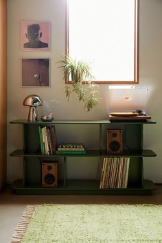 a green shelf with records, record players and a plant