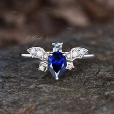 a blue and white diamond ring sitting on top of a rock