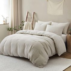 a bed with white linens and pillows in a small room next to a window