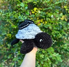 a hand holding up a crocheted stuffed animal with a hat on it's head