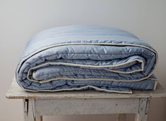 a blue comforter sitting on top of a wooden table next to a white wall