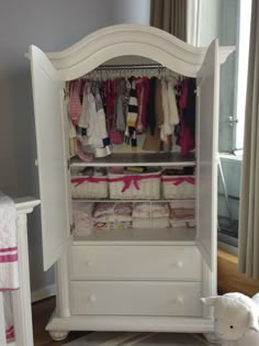 a baby's closet with white furniture and pink accessories on the floor next to a teddy bear