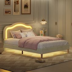 a bedroom with a lit up bed in the middle and pictures on the wall behind it