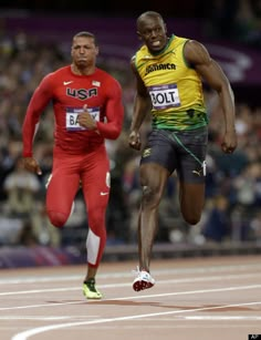 two men running on a track with spectators in the background