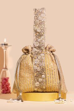 a gold purse sitting on top of a table next to a vase and candle holder