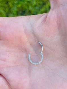 a person's hand holding a small crescent shaped earring