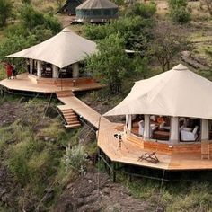 several tents set up in the middle of a grassy area with stairs leading to them