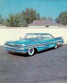 an old blue car parked in a parking lot