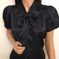 Authentic Prada Black Satin Silk Blouse. Size 42. Except Condition. No Issues. Short With Pleads. Front Banded Buttons Front Closure With Ruffles. Banded Collar With Long Ribbons For Lend Tie. Gorgeous Satin Silk Has Some Stretch. Bust- 38”, Waist-38”, Shoulders- 14”,Center Back Length-23”. Designer Satin Tops For Workwear, Designer Satin Blouse For Work, Elegant Short Sleeve Party Blouse, Classic Black Satin Top, Elegant Short Sleeve Blouse For Night Out, Black Fitted Shirt For Evening, Designer Short Sleeve Formal Tops, Classic Black Satin Blouse, Designer Fitted Evening Blouse